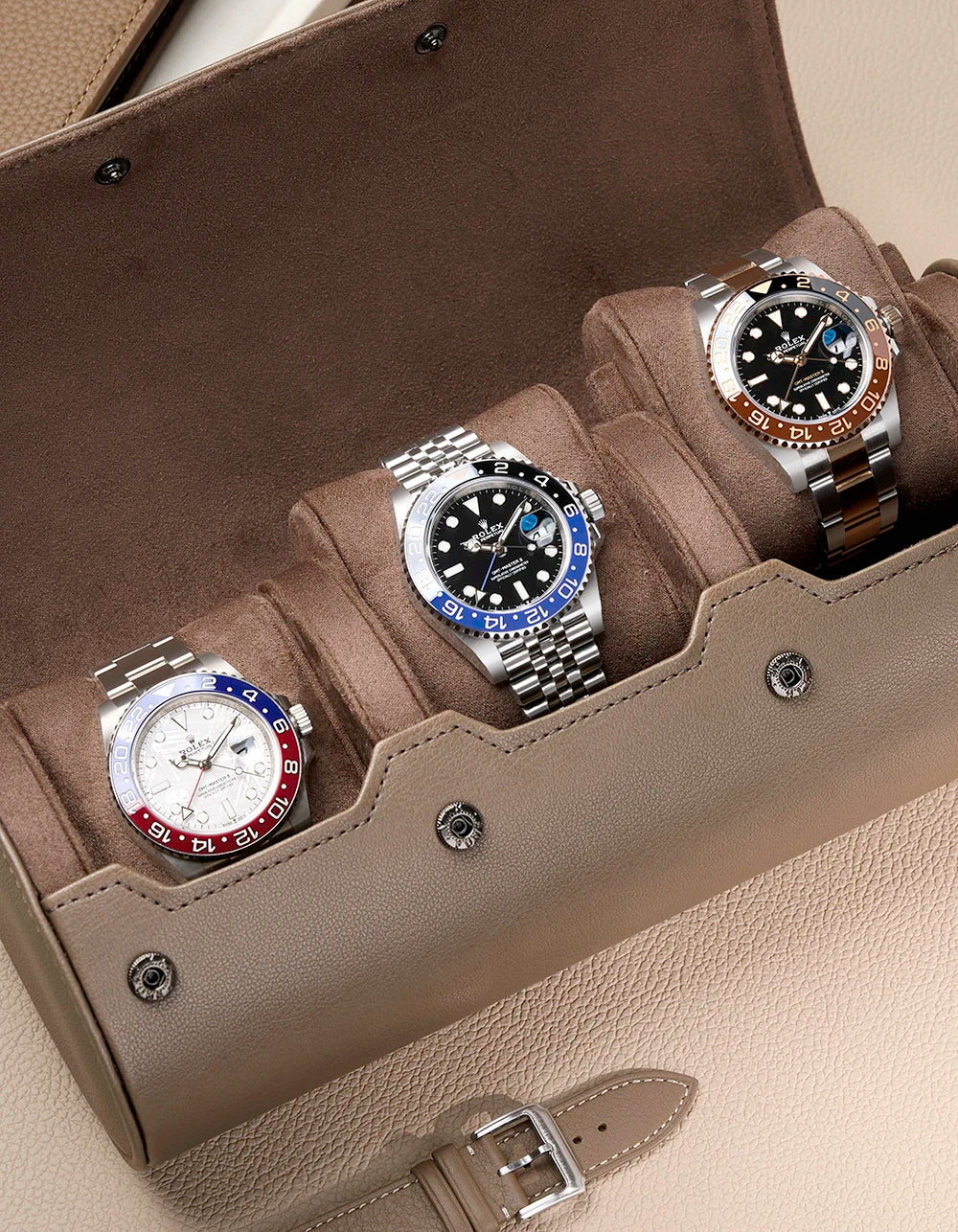 Three watches in a display case on a beige surface