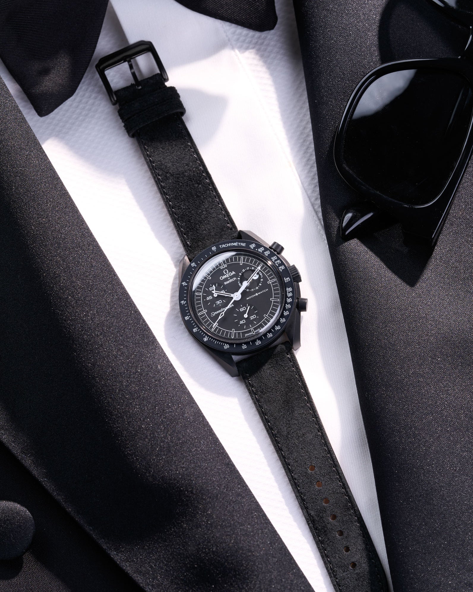 Flat lay Moonswatch Mission to the Moonphase New Moon with Black suede leather strap