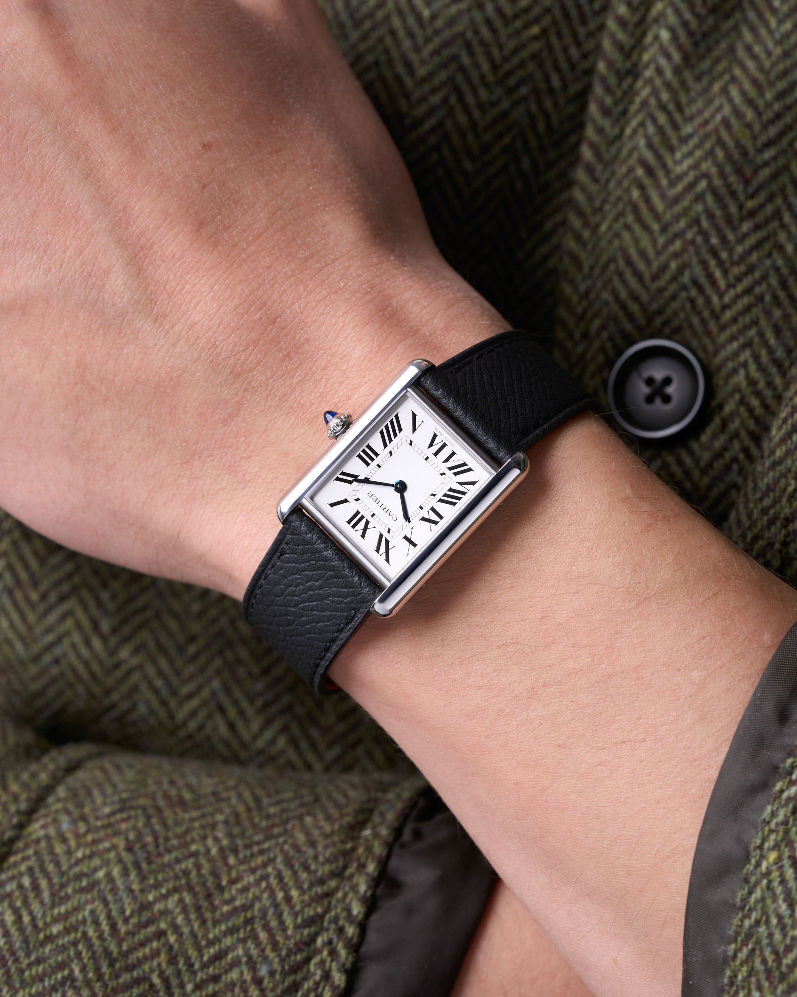 Cartier Tank on a black epsom leather watch strap on a wrist.