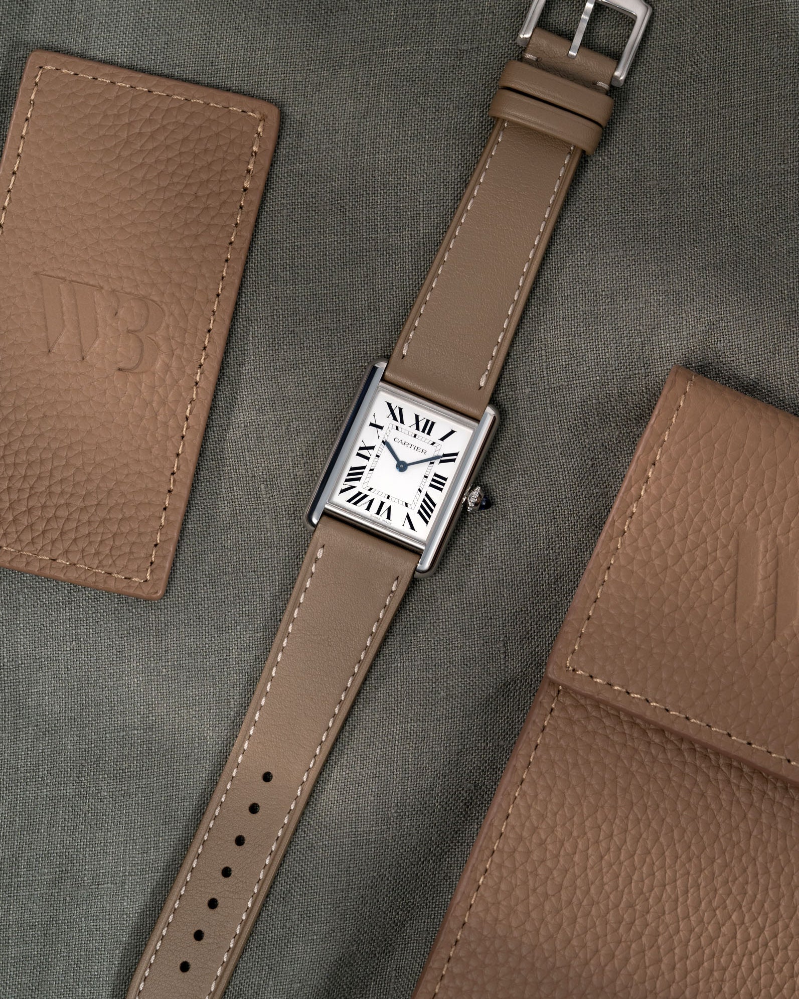 Luxury Cartier Tank Must Large with Taupe Cowhide Leather strap, photographed in flat lay style with clasp over green table