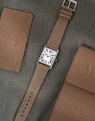 Luxury Cartier Tank Must Large with Taupe Cowhide Leather strap, photographed in flat lay style with clasp over green table