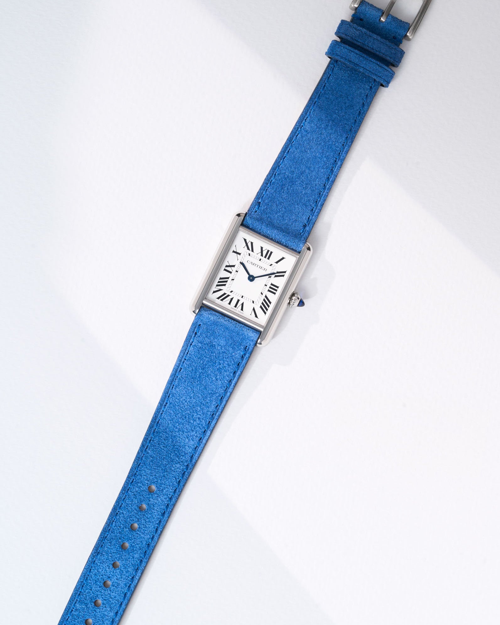 Cartier Tank Must Large watch with Ocean Blue Suede Leather strap, lying flat on white background