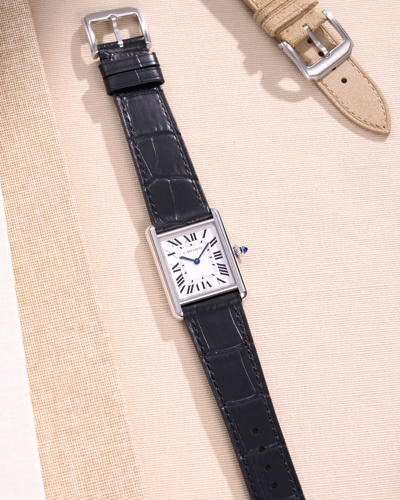 Cartier watch with sleek black alligator leather strap on a beige background