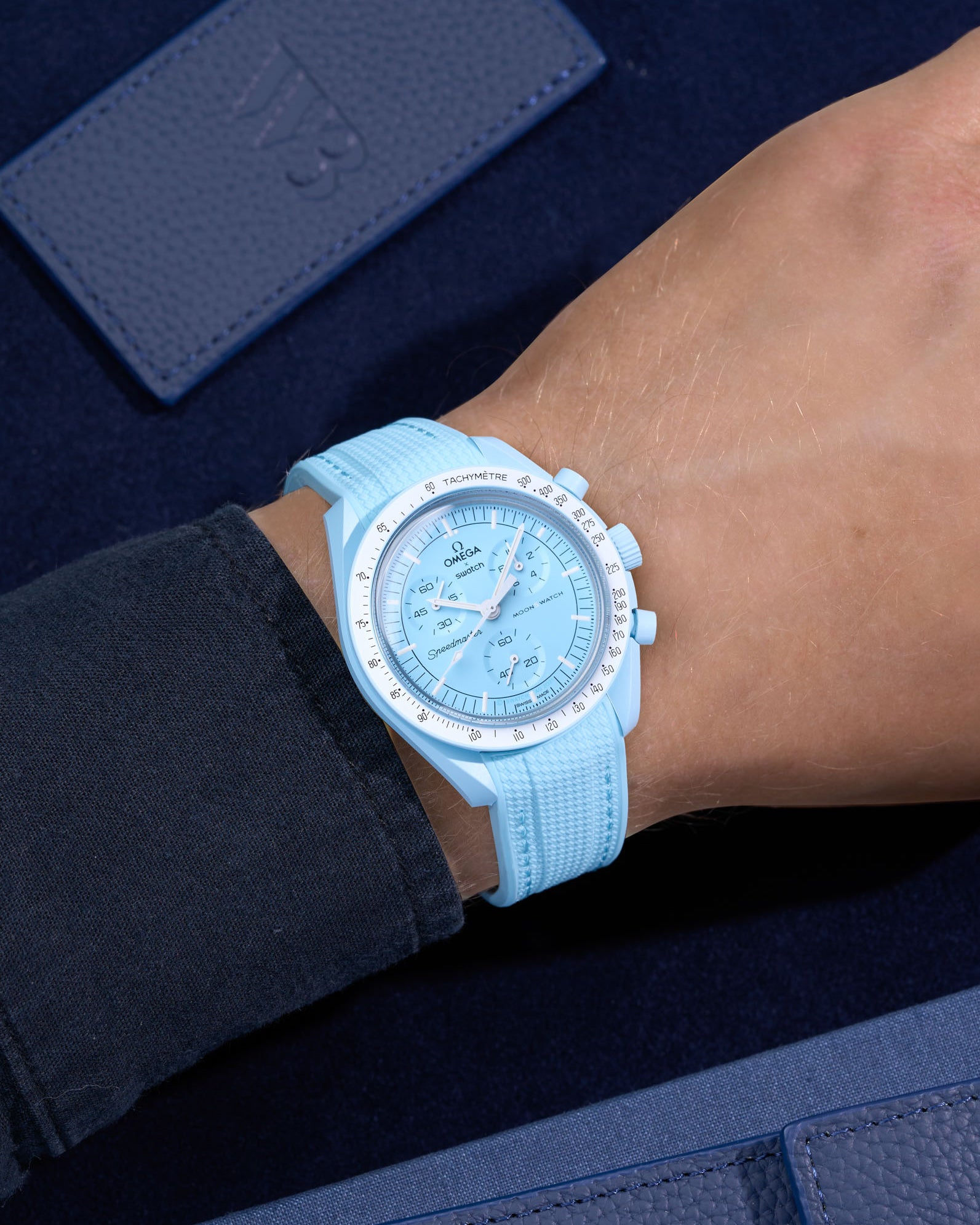 Turquoise Rubber Strap on Omega X Swatch MoonSwatch Mission to Uranus wrist shot with dark blue shirt and blue background