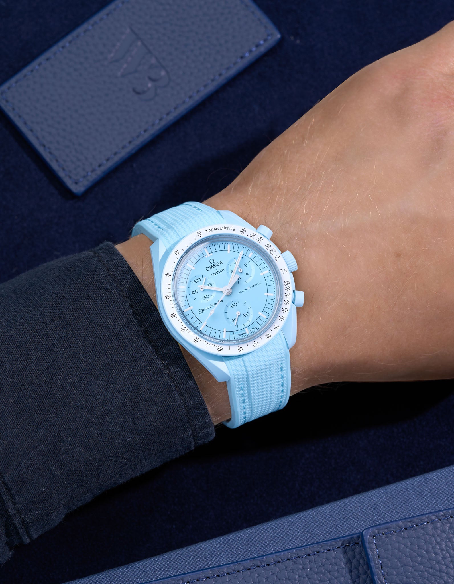 Turquoise Rubber Strap on Omega X Swatch MoonSwatch Mission to Uranus wrist shot with dark blue shirt and blue background