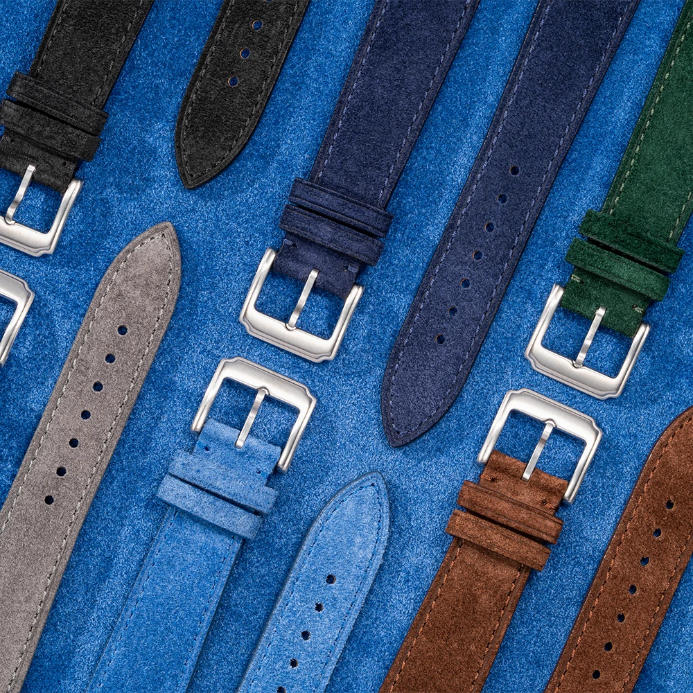 Collection of suede leather watch straps in various colors with stainless steel buckles displayed on blue suede background