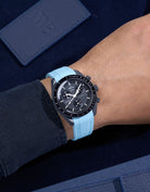 MoonSwatch Mission to Mercury on wrist with vertech turquoise rubber strap and a dark blue shirt