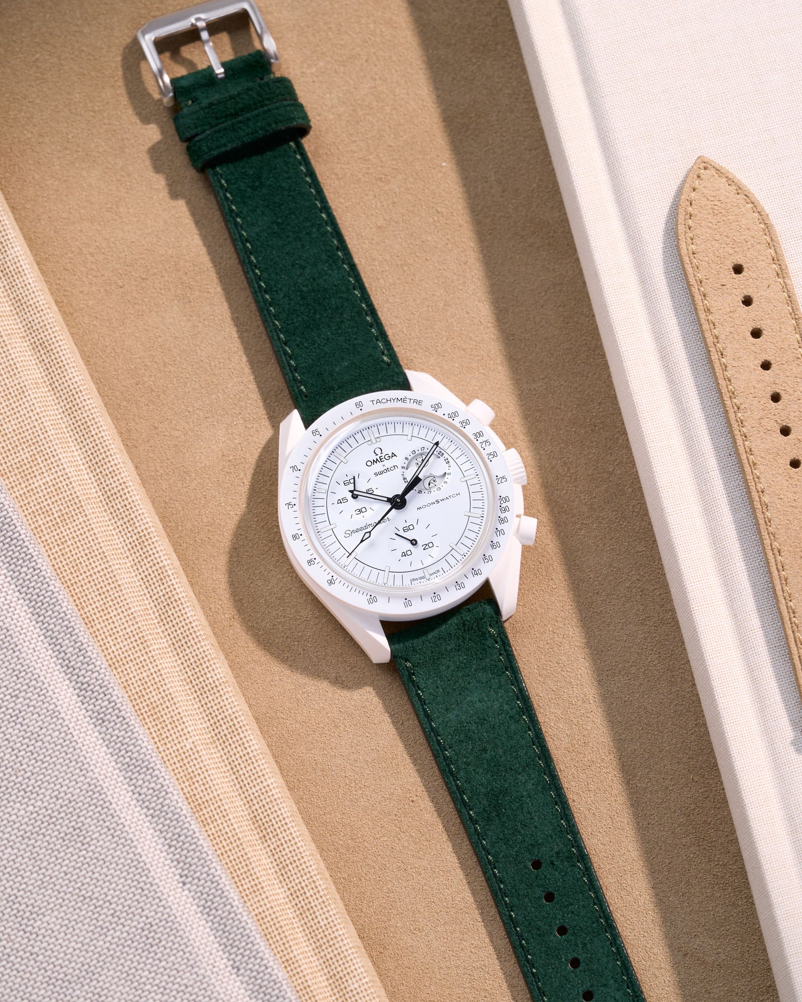 Flat lay Moonswatch Mission to the Moonphase Full Moon with Dark Green suede leather strap