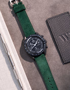Flat lay Moonswatch Mission to the Moonphase New Moon with Dark Green suede leather strap