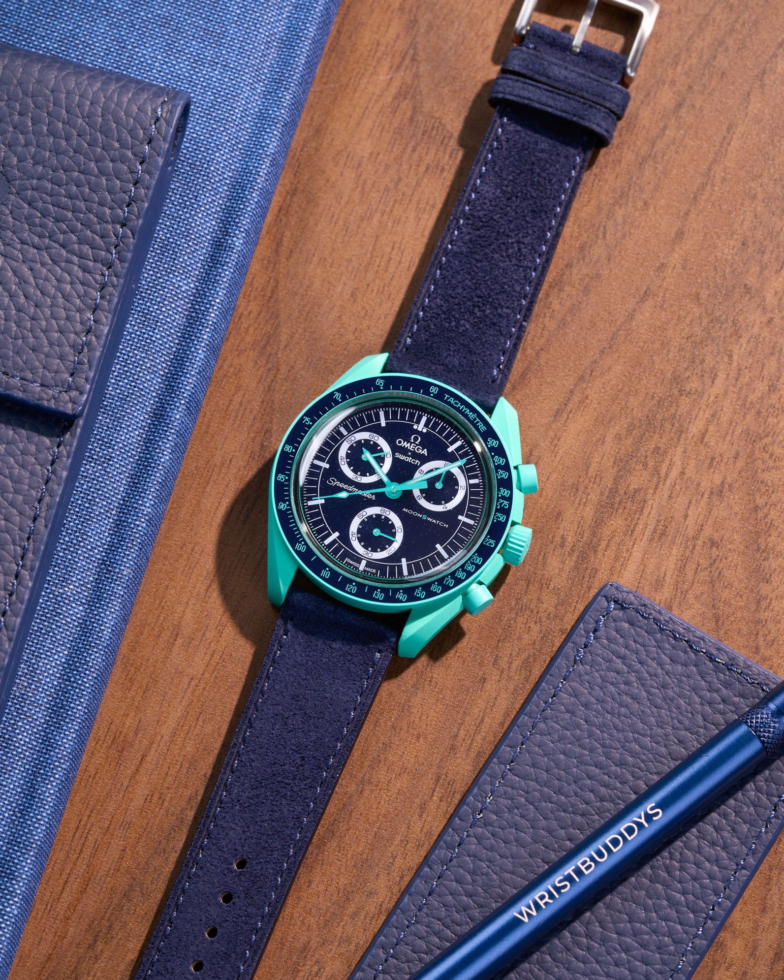 Flat lay Moonswatch Mission on Earth Polar Lights with Dark Blue suede leather strap
