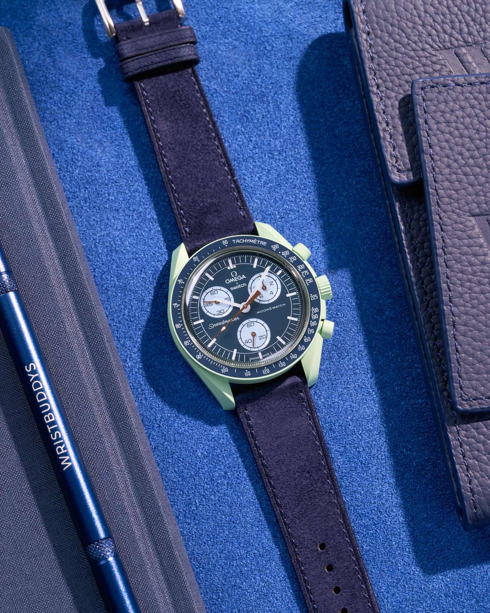Flat lay Moonswatch Mission on Earth with Dark Blue suede leather strap