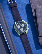 Flat lay Moonswatch Mission on Earth with Dark Blue suede leather strap
