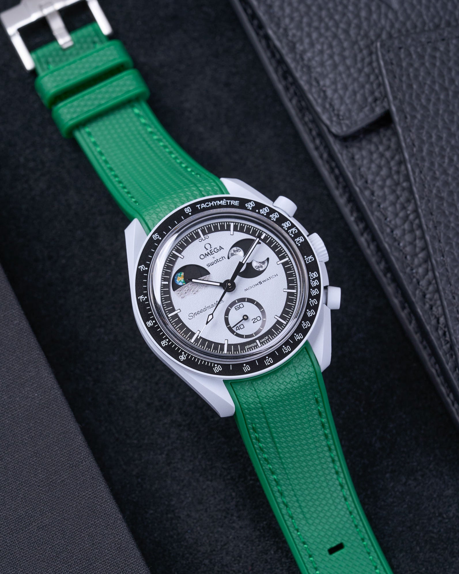 Flat lay of MoonSwatch Mission to EarthPhase with green rubber strap, watch facing up with clasp visible