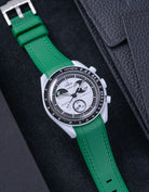 Flat lay of MoonSwatch Mission to EarthPhase with green rubber strap, watch facing up with clasp visible