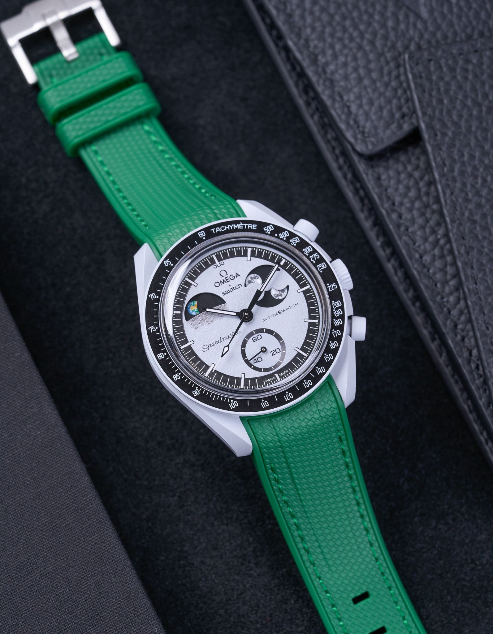 Flat lay of MoonSwatch Mission to EarthPhase with green rubber strap, watch facing up with clasp visible