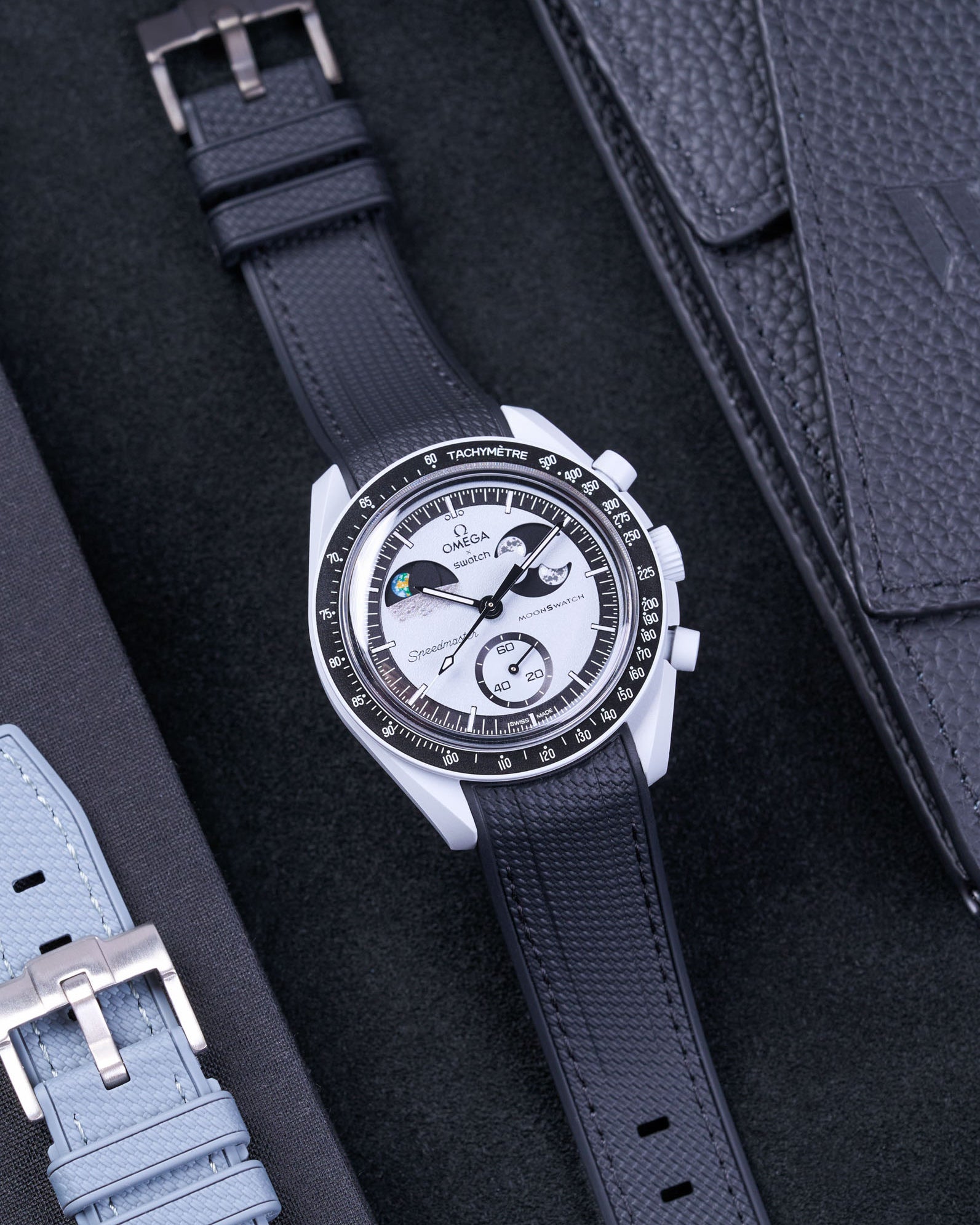 Flat lay of Vertech Omega X Swatch MoonSwatch Mission to EarthPhase with black rubber strap, watch facing up with clasp visible
