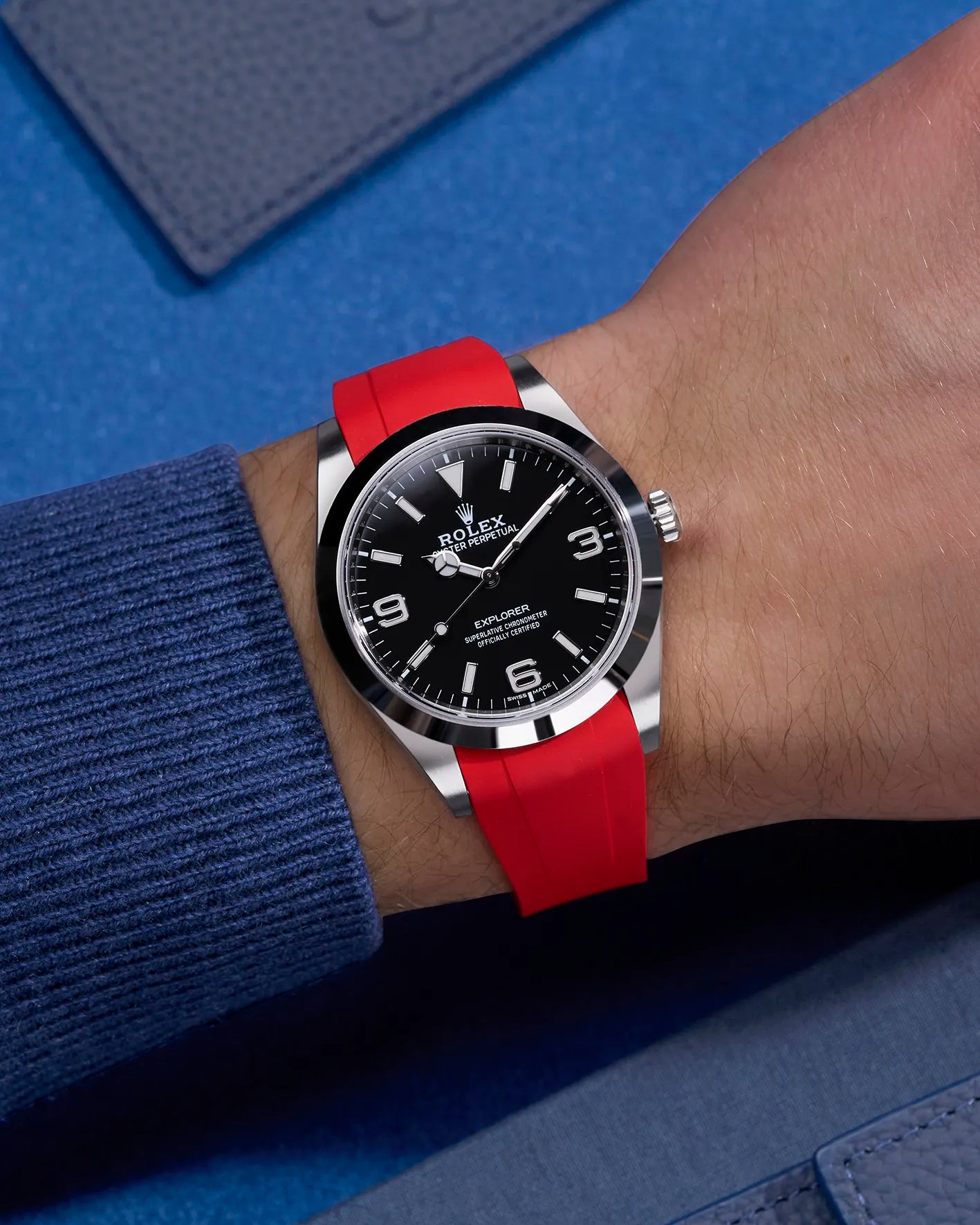 Red integrated rubber strap with original clasp on Rolex Explorer 214270 – wrist shot with navy blue tones