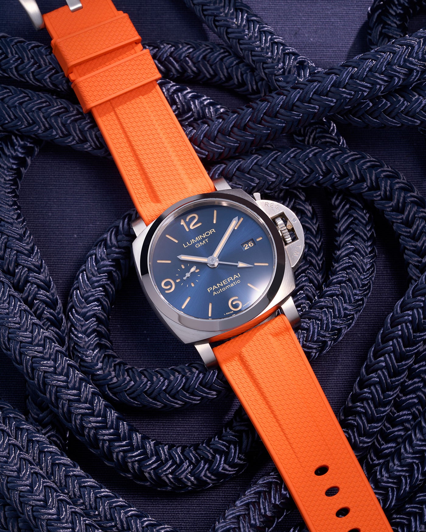 Panerai Luminor GMT Blue Dial with Orange Rubber Strap against Navy Nautical Ropes – Iconic Swiss Made luxury watch in polished stainless steel, paired with a bold 24mm orange rubber uhrenband, perfect for adventurers who value high-visibility design. This Panerai model features a GMT function for dual-time tracking, enhanced by the vibrant orange strap that adds a contemporary twist to traditional luxury, ideal for outdoor activities and nautical-inspired style.