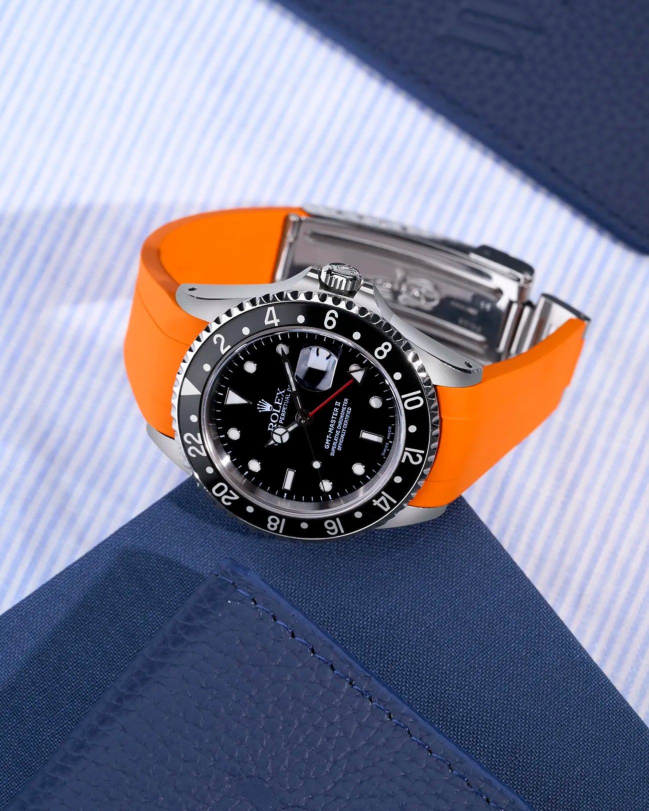 Rolex GMT-Master II 16710 and 16713 with integrated orange rubber strap and original clasp – flat lay scene