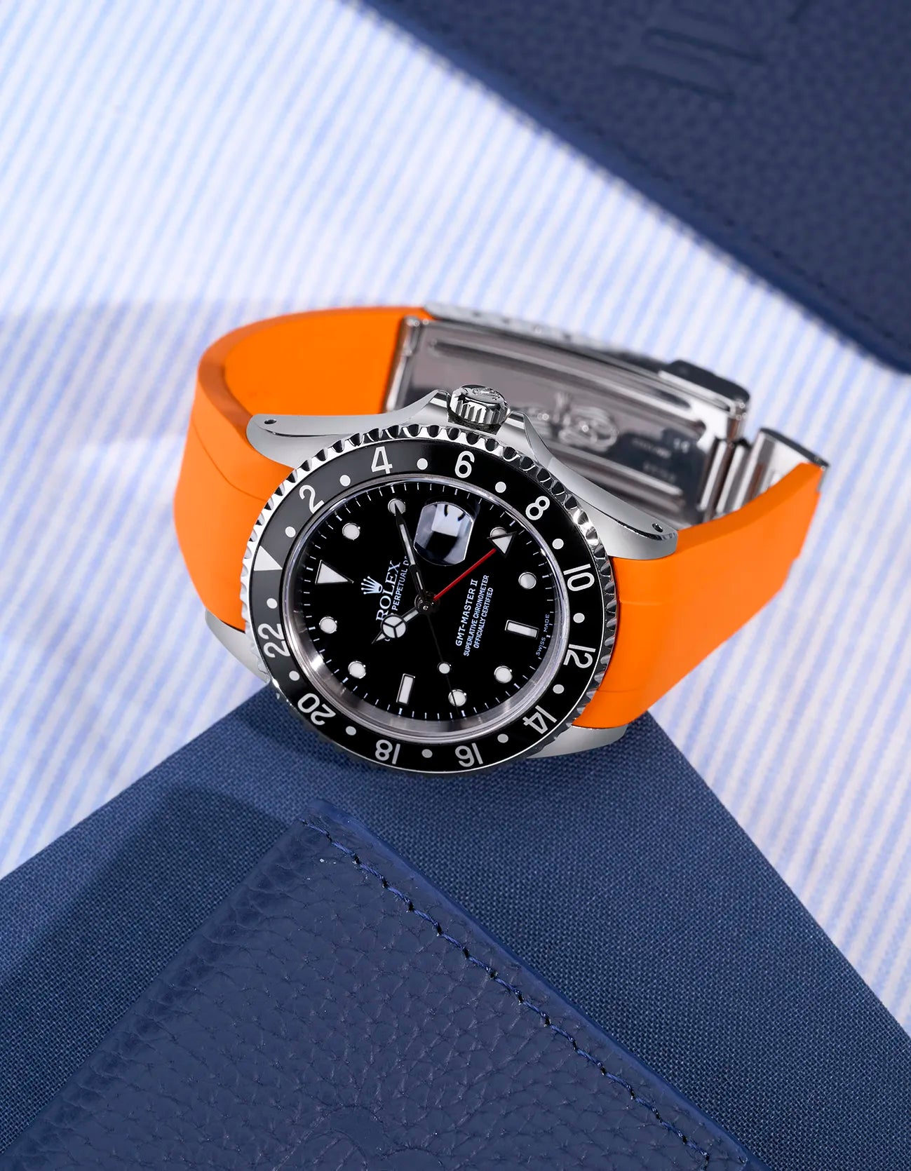Rolex GMT-Master II 16710 and 16713 with integrated orange rubber strap and original clasp – flat lay scene