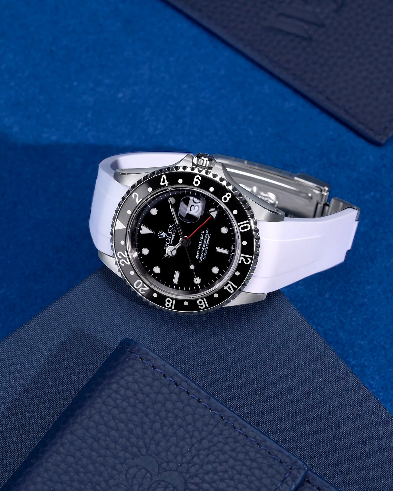 Rolex GMT-Master II 16710 and 16713 with white FKM rubber strap and original clasp – flat lay on blue background