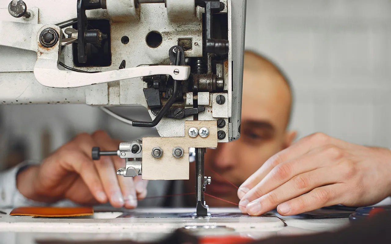 Craftsman hand-finishing a Wristbuddys rubber watch strap using industrial sewing machine for premium comfort