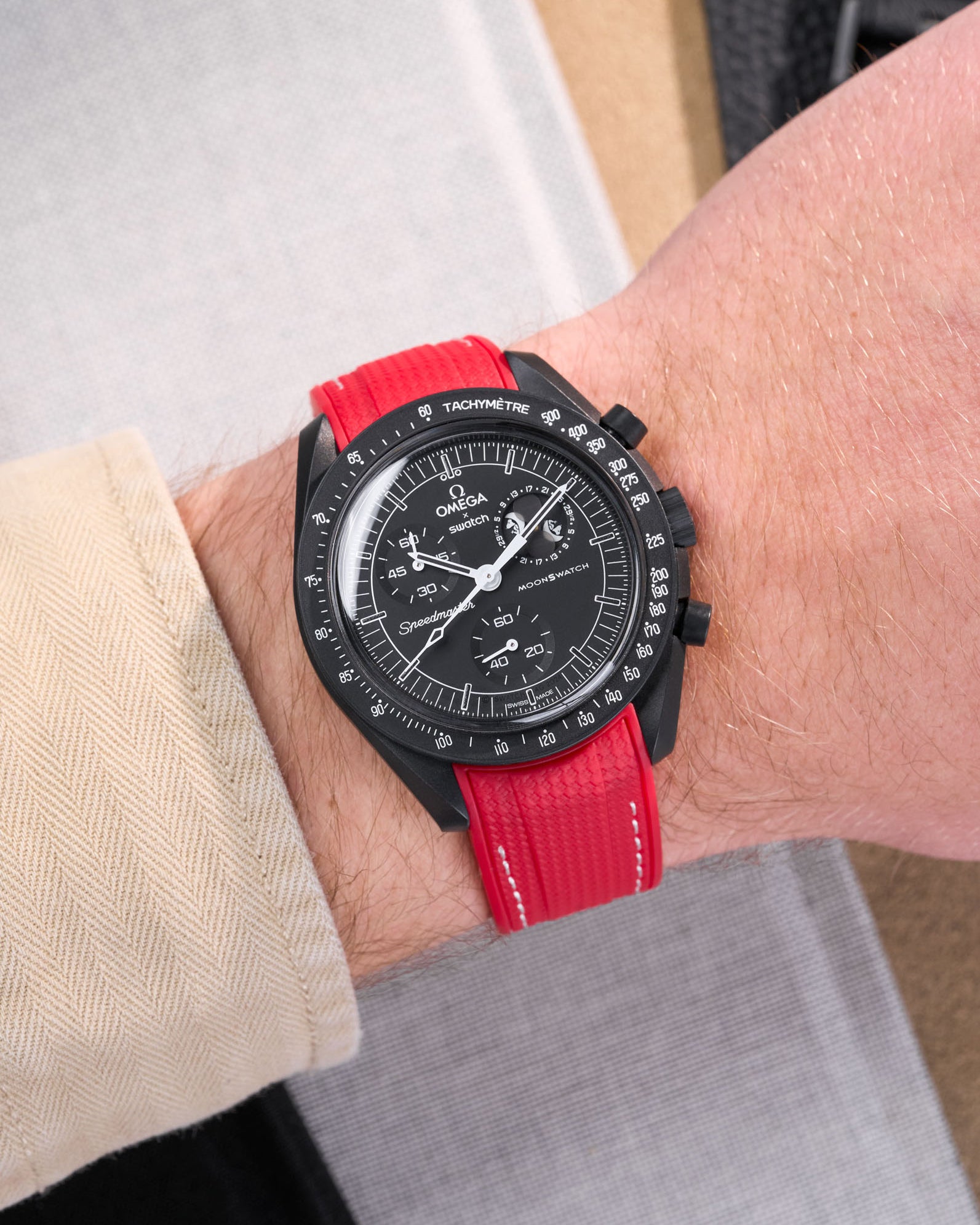 MoonSwatch Mission to Moonphase New Moon on the wrist with vertech red rubber strap with white stitching styled with beige shirt