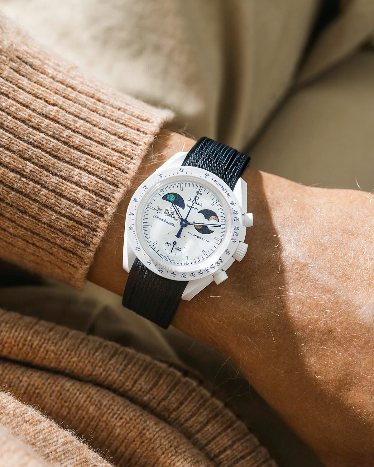 Black rubber strap on Moonswatch Moonshine Gold Cold Moon wrist shot with brown shirt