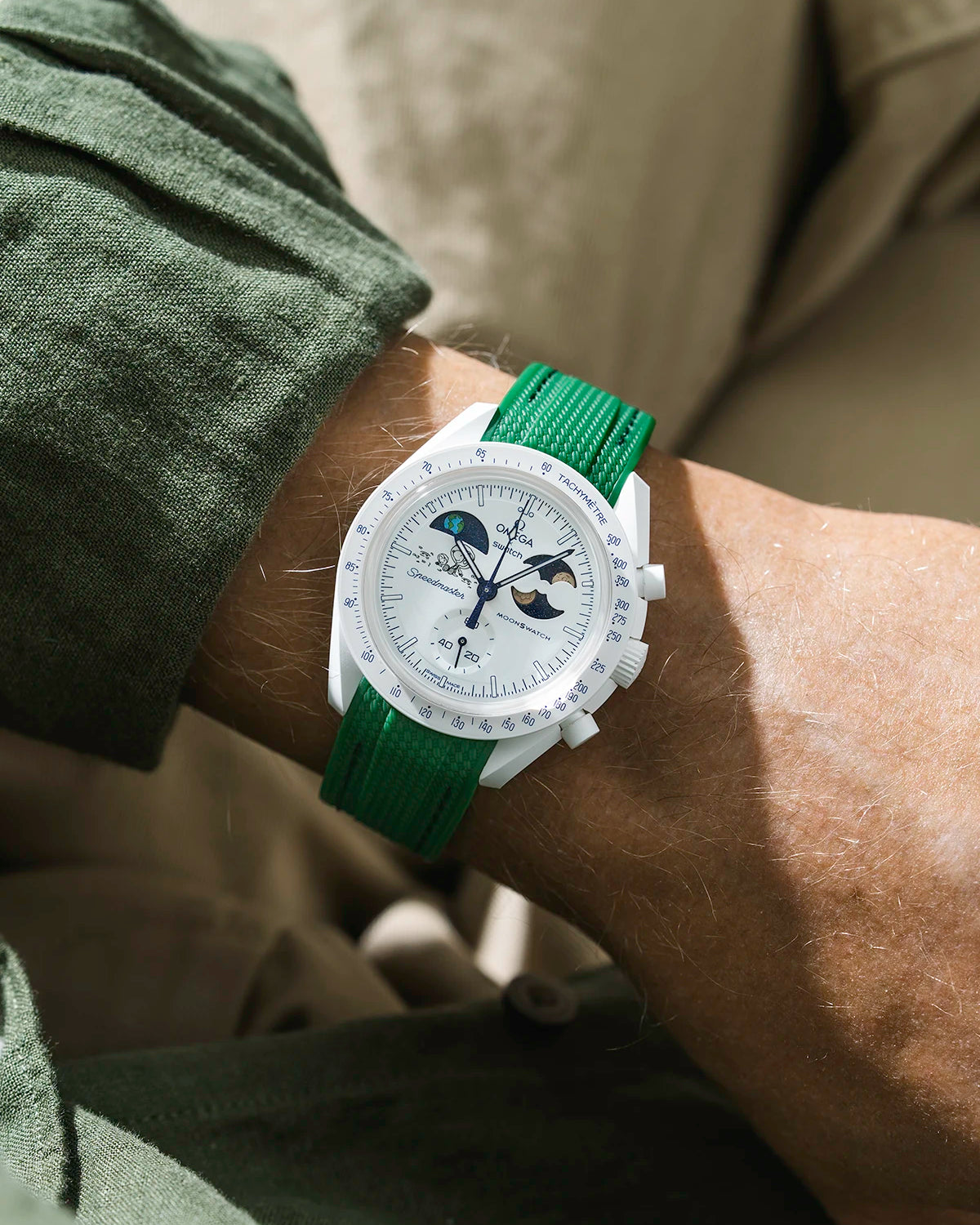 Green rubber strap on Moonswatch Moonshine Gold Cold Moon watch wrist shot with green shirt