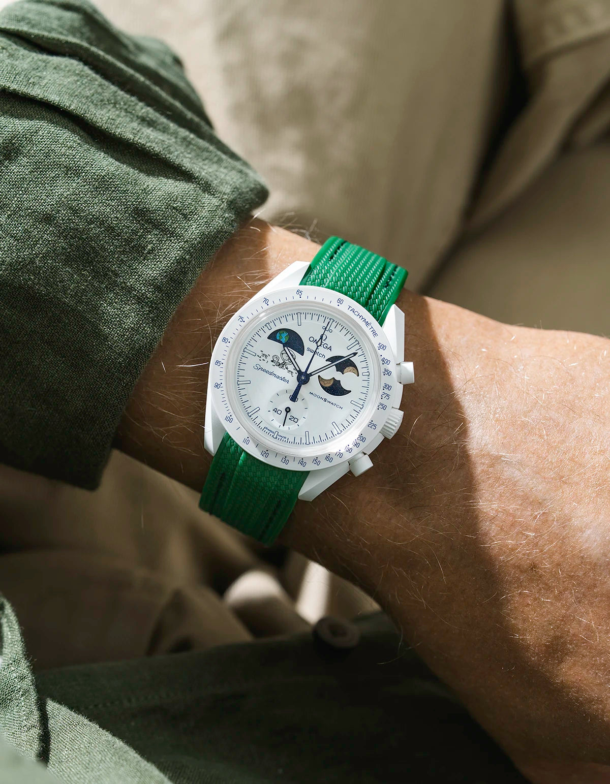 Green rubber strap on Moonswatch Moonshine Gold Cold Moon watch wrist shot with green shirt