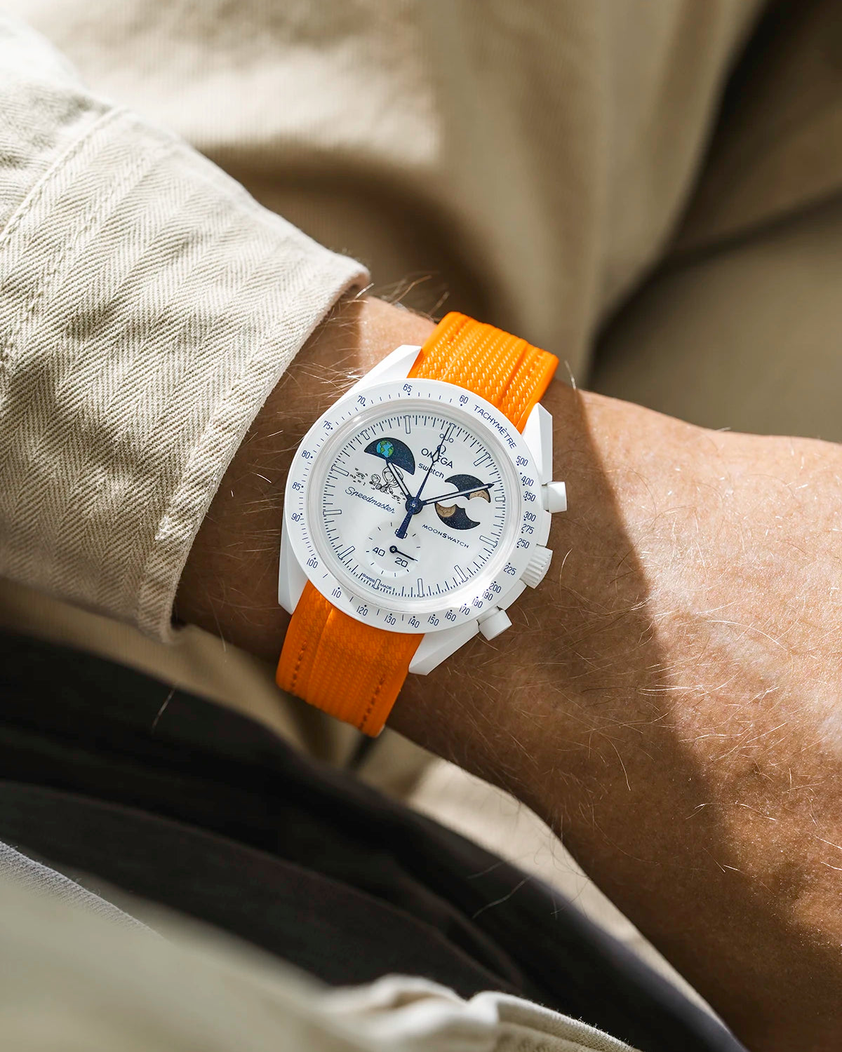Orange rubber strap on Moonswatch Moonshine Gold Cold Moon wrist shot with beige shirt