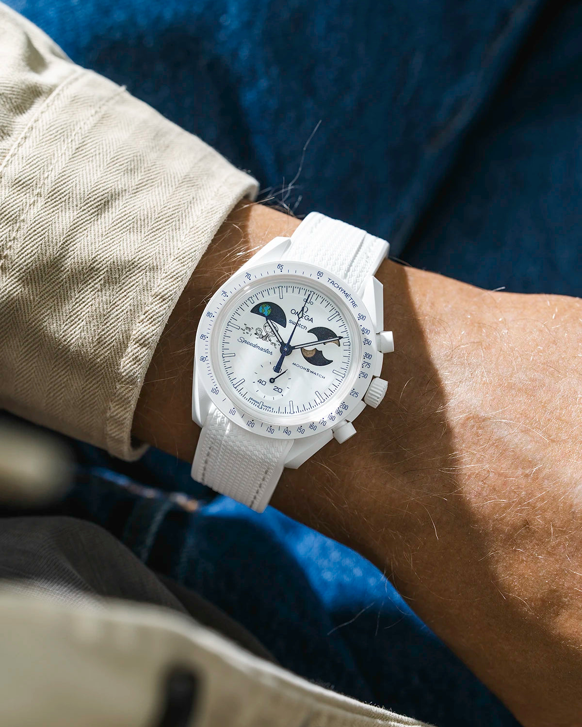 White rubber strap on Moonswatch Moonshine Gold Cold Moon watch wrist shot with beige shirt