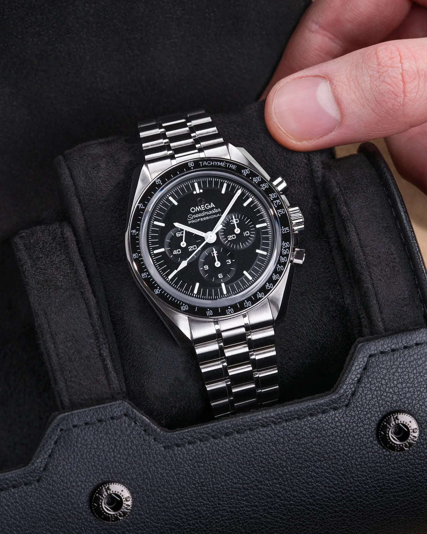 Black watch roll with Sliding System, showcasing an Omega Speedmaster stainless steel watch on a soft velvet sliding cushion for secure and stylish storage