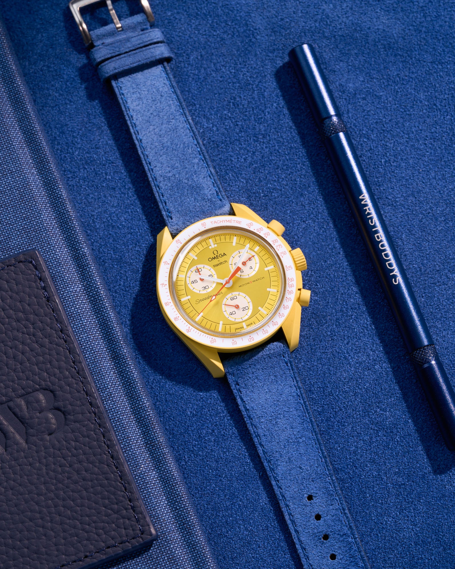 Flat lay Moonswatch Mission to the Sun with Ocean Blue suede leather strap