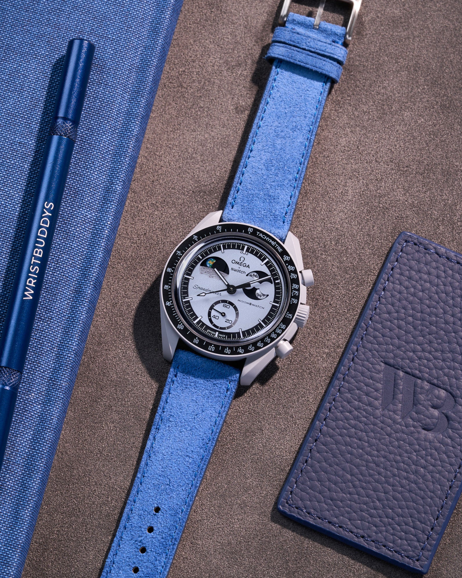 Flat lay Moonswatch Mission to Earthphase with Ocean blue suede leather strap