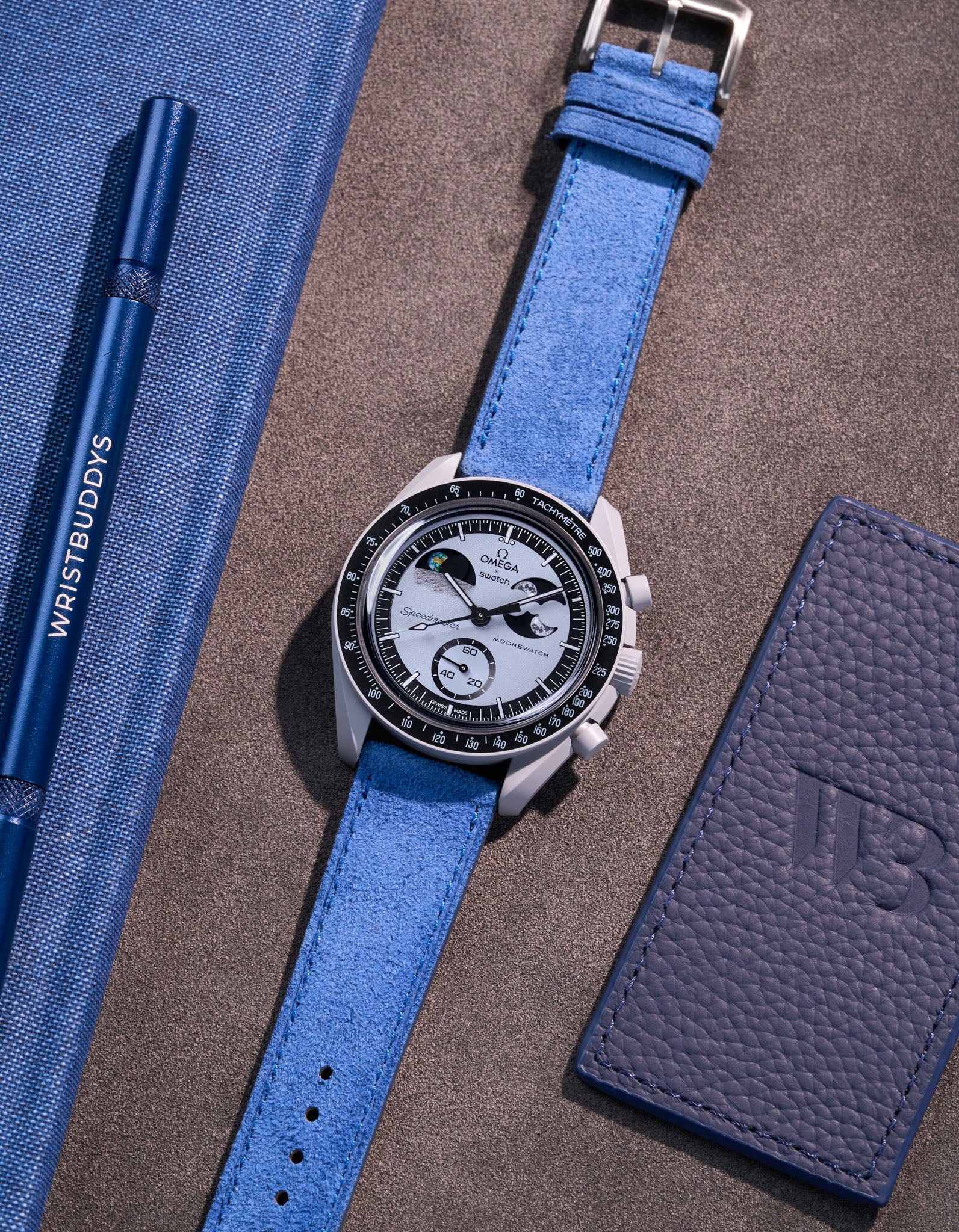 Flat lay Moonswatch Mission to Earthphase with Ocean blue suede leather strap