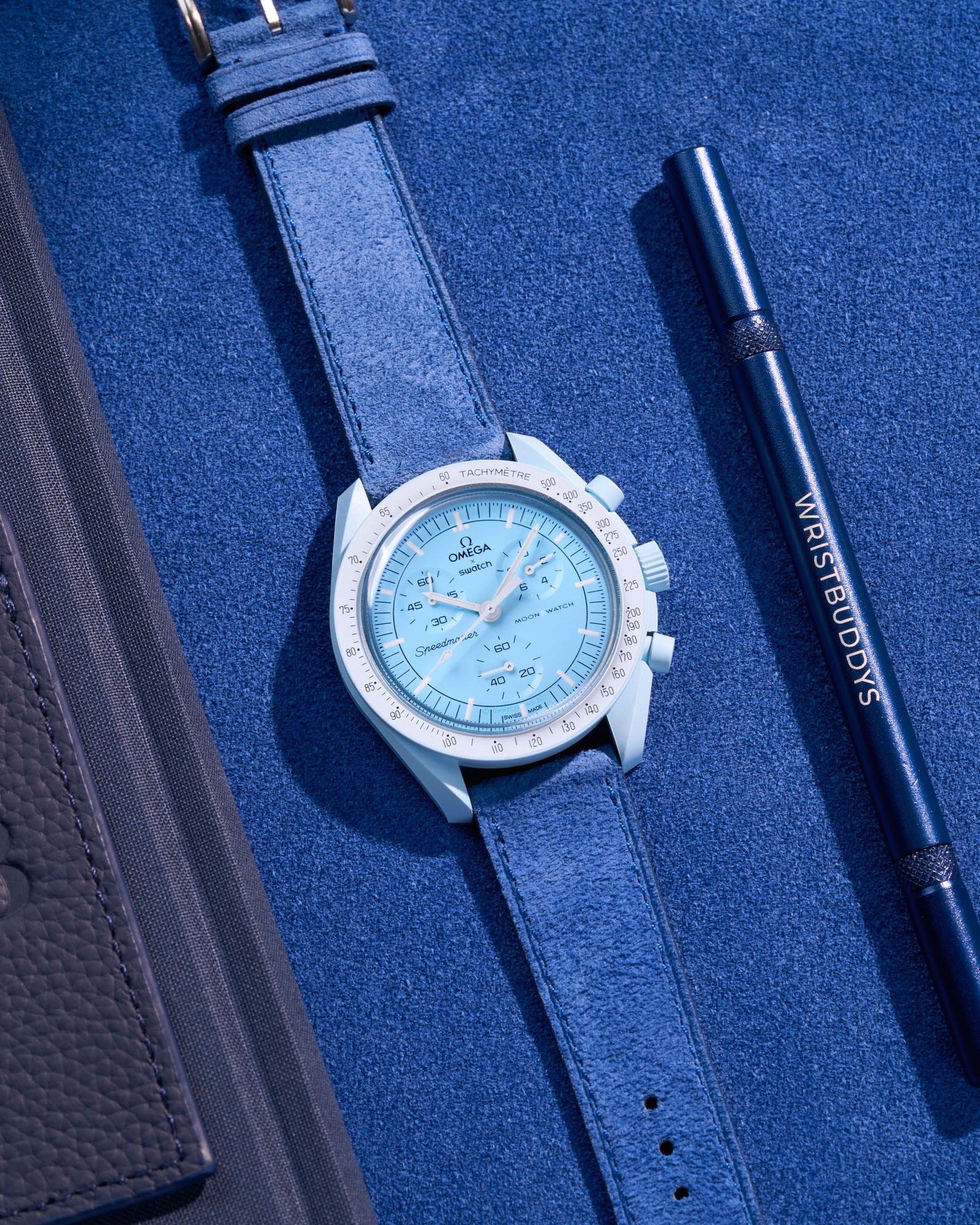 Flat lay Moonswatch Mission to Uranus with Ocean Blue suede leather strap
