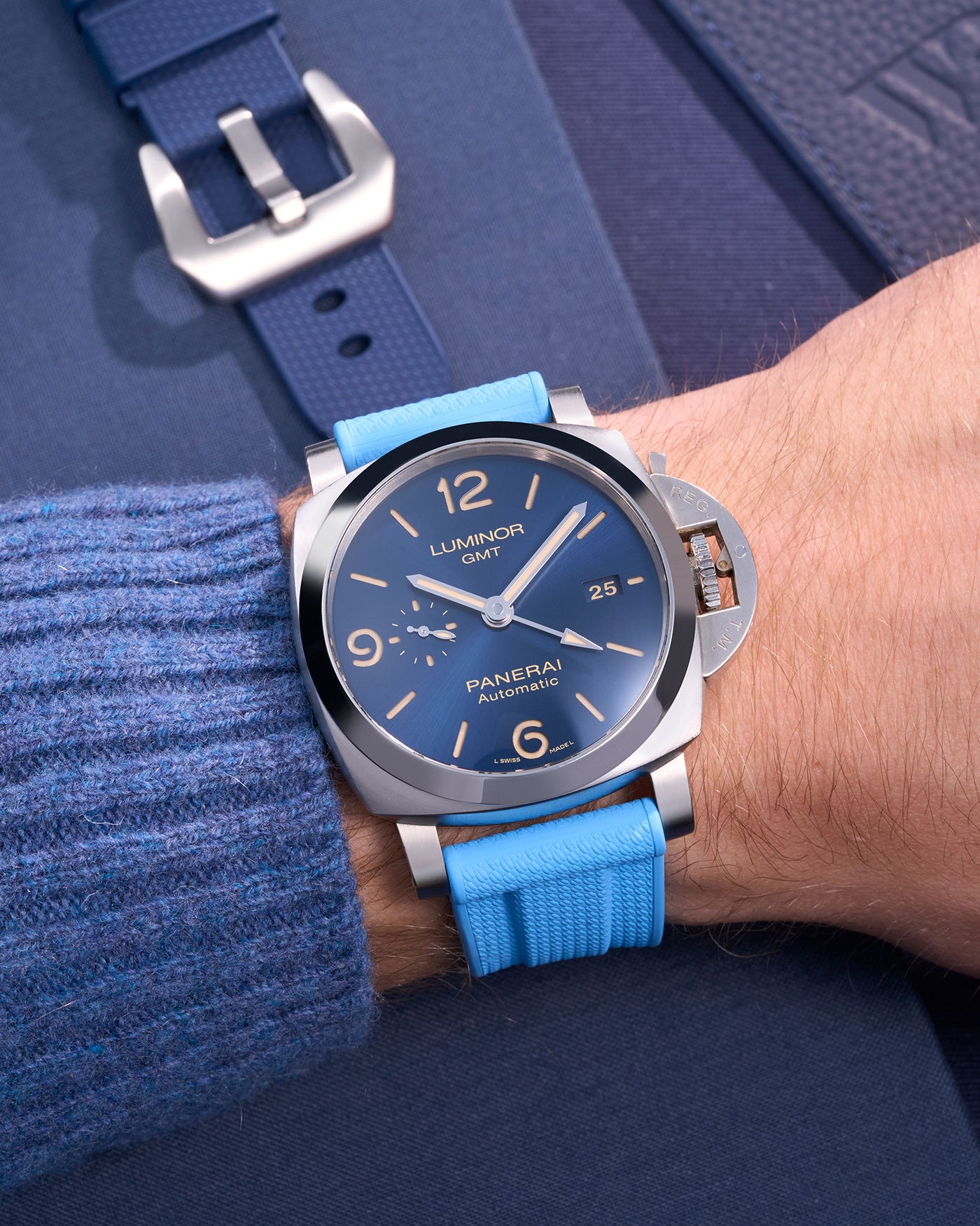 Panerai Luminor GMT Blue Dial with Capri Blue Rubber Strap on Wrist – Swiss Made Panerai med polerad rostfri stålboett och ett färgstarkt ljusblått 24mm gummiband, idealiskt för utomhusäventyr och stilmedvetna bärare. Klockan erbjuder GMT-funktion för dubbel tidszon, vilket gör den praktisk för resande och affärsresenärer. Det ljusblå armbandet tillför en ungdomlig och modern touch till Panerais klassiska design.