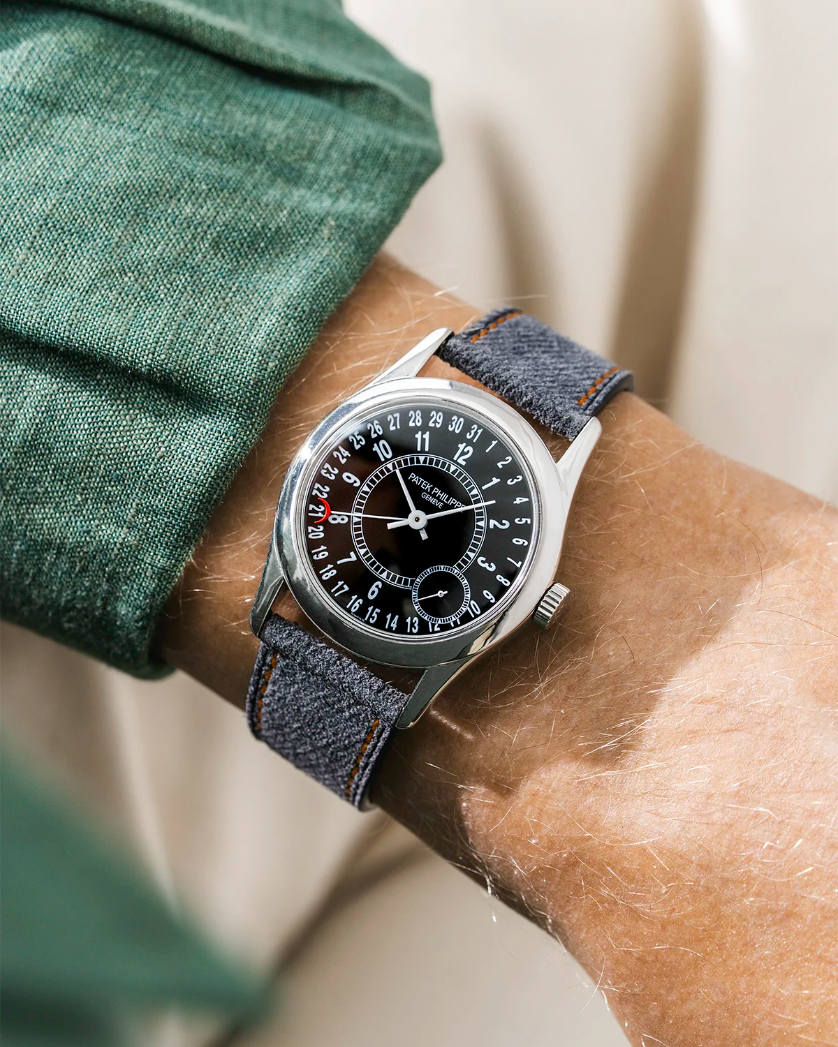 Patek Calatrava on a black denim leather watch strap from Wristbuddys on a persons wrist wearing a green shirt