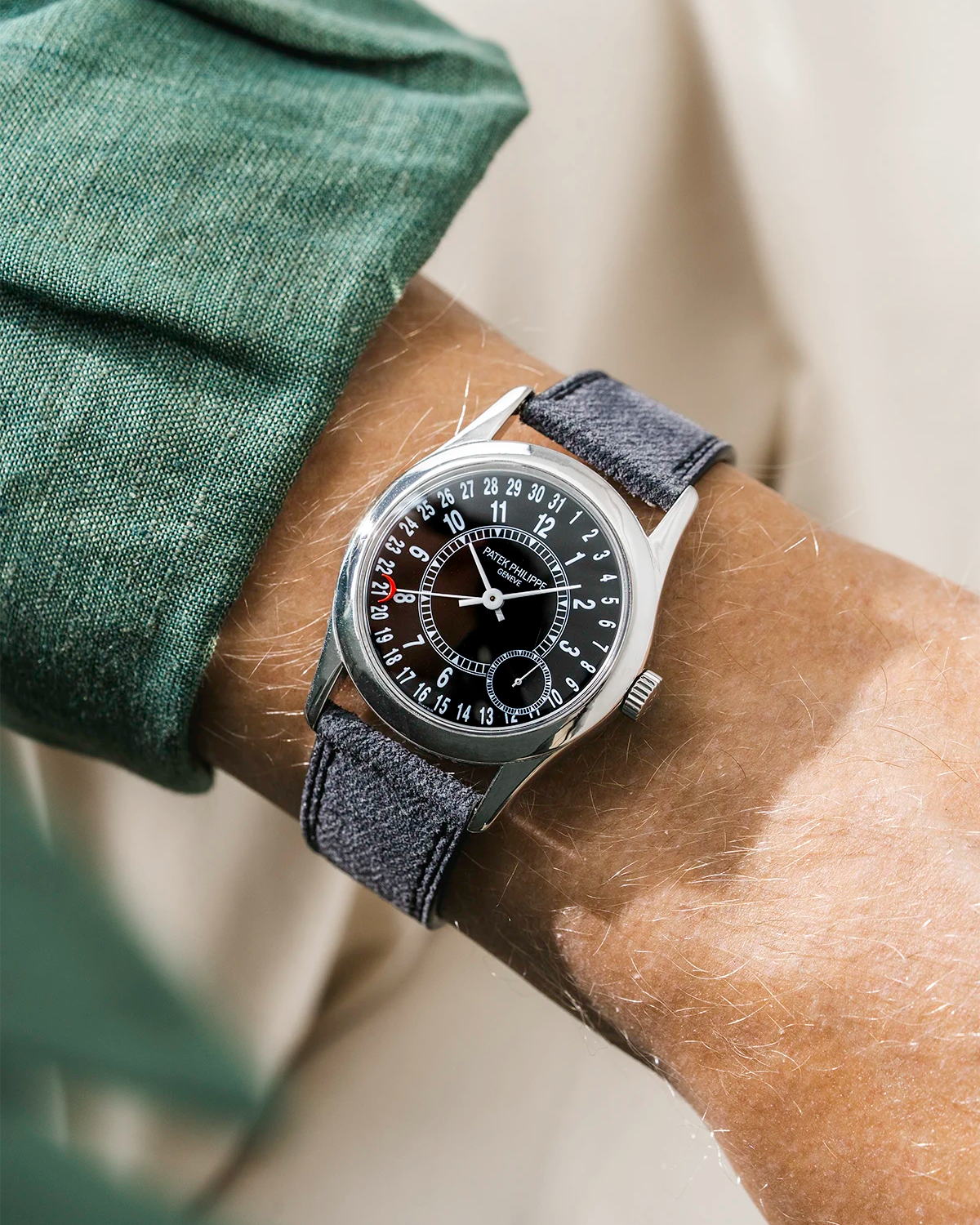 Patek Calatrava on a black denim leather watch strap from Wristbuddys on a persons wrist wearing a green shirt