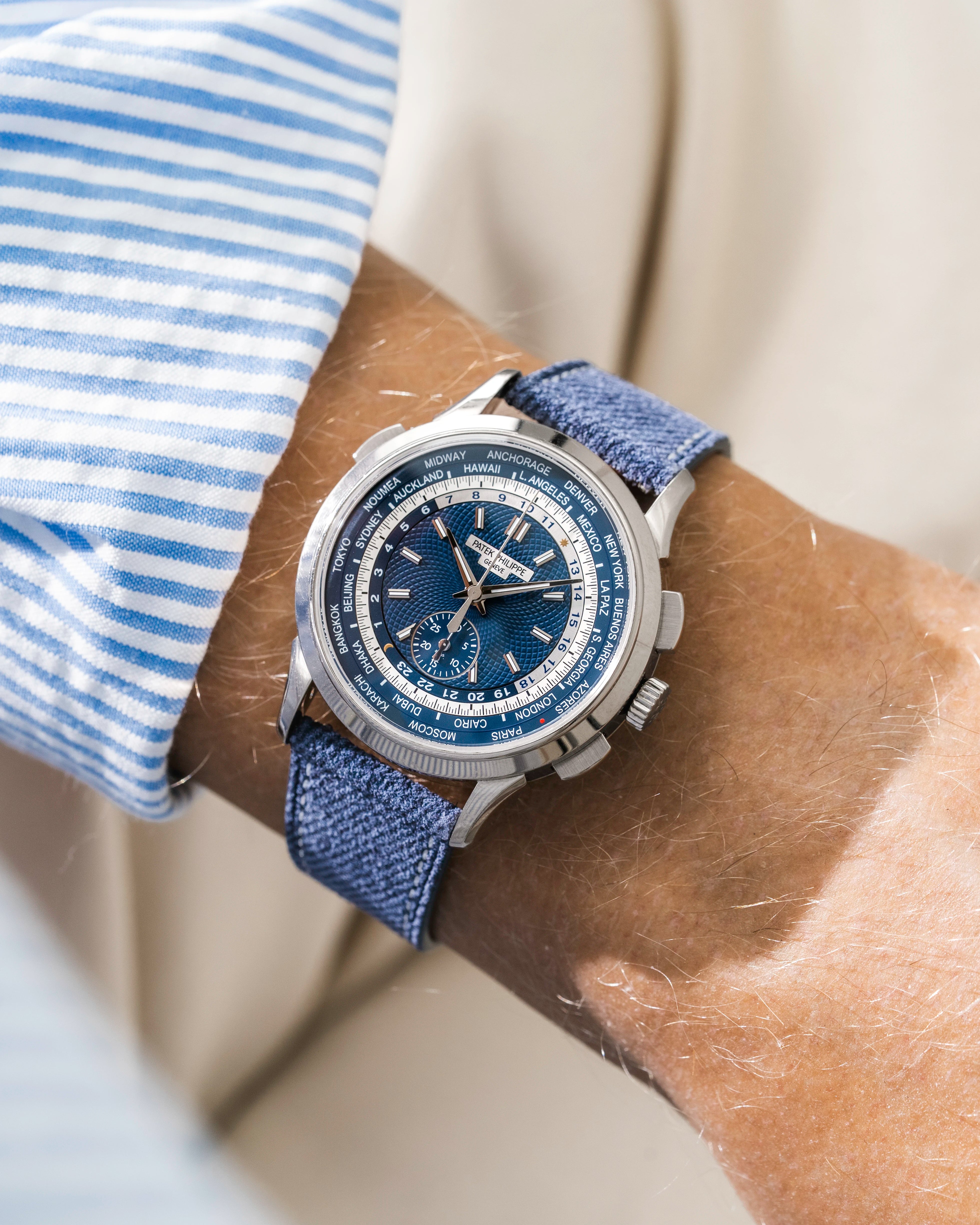 Patek Worldtimer on a blue denim leather watch strap from Wristbuddys on a persons wrist wearing a blue striped shirt