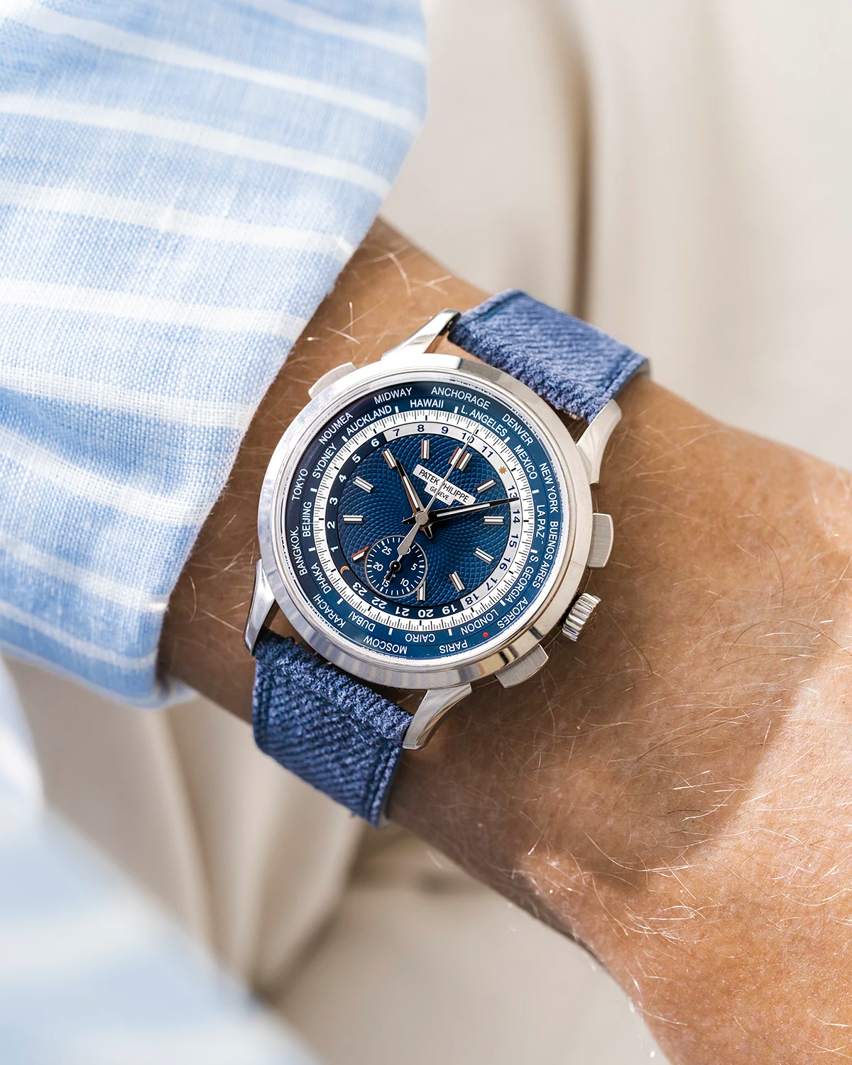 Patek Worldtimer on a blue denim leather watch strap from Wristbuddys on a persons wrist wearing a blue striped shirt