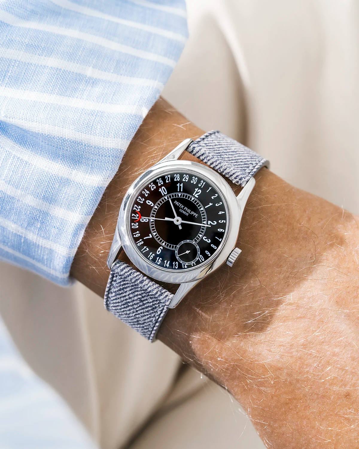 Patek Calatrava on a light grey denim leather watch strap from Wristbuddys on a persons wrist wearing a blue striped shirt