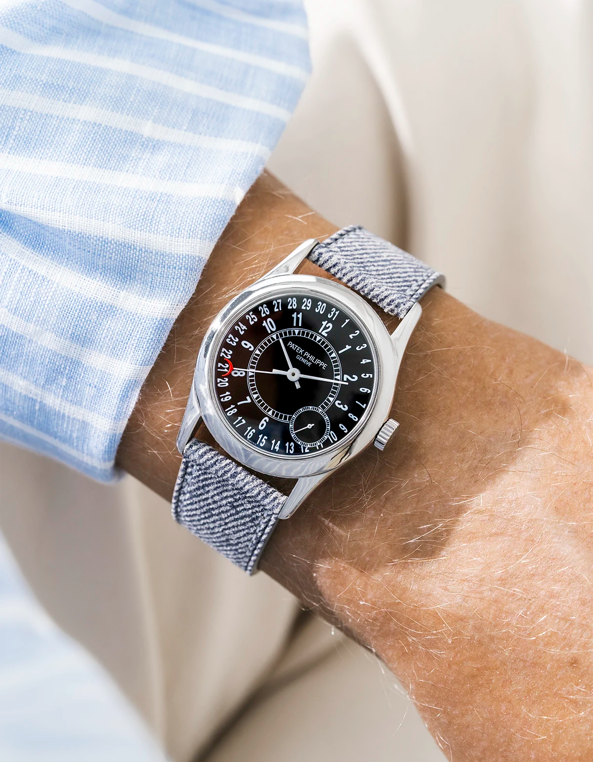 Patek Calatrava on a light grey denim leather watch strap from Wristbuddys on a persons wrist wearing a blue striped shirt