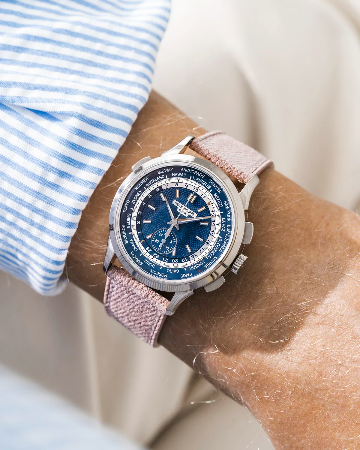 Patek Worldtimer on a pink denim leather watch strap from Wristbuddys on a persons wrist wearing a blue striped shirt