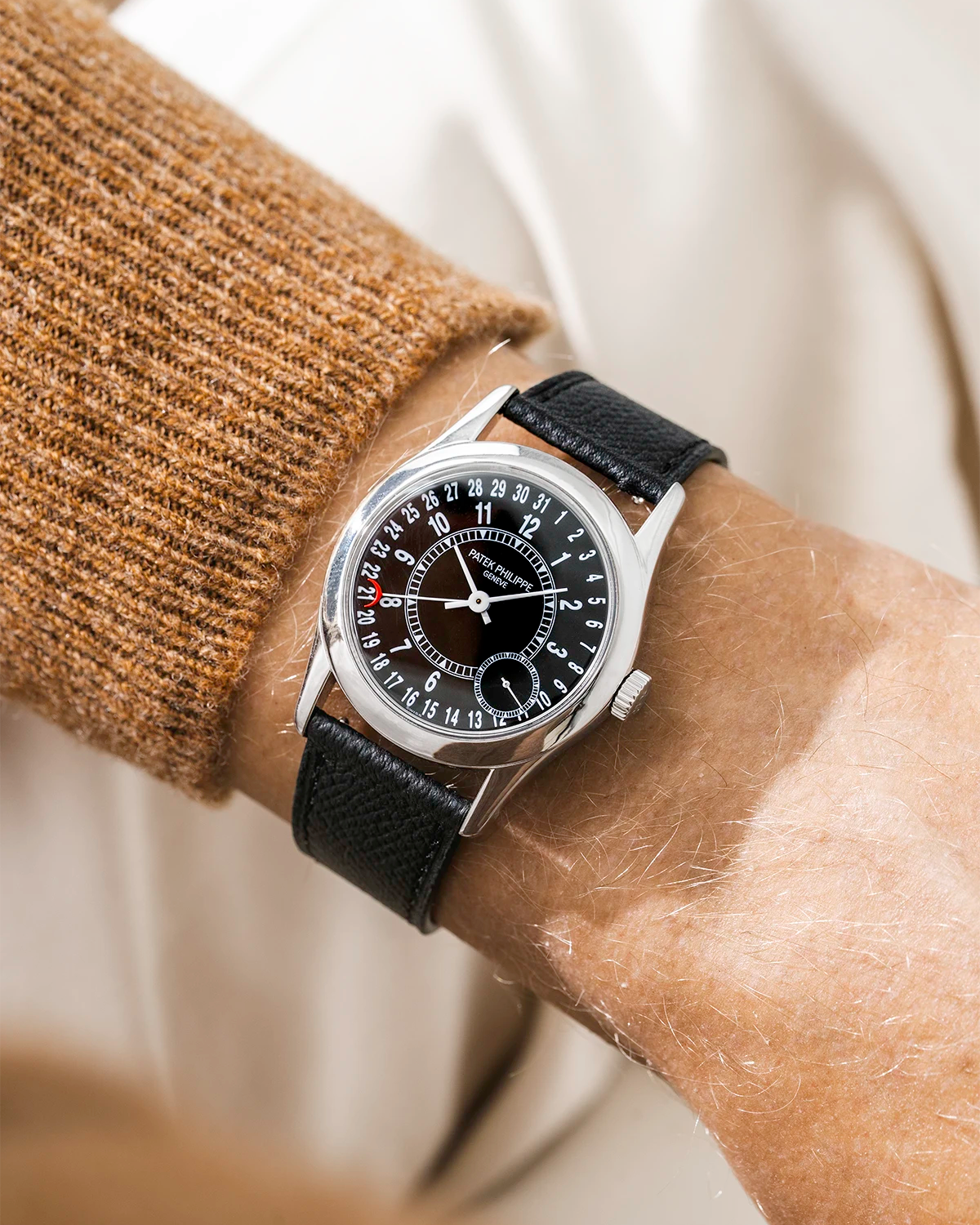 Patek Calatracva on a black epsom leather strap from Wristbuddys on a persons wrist with a beige/brown shirt