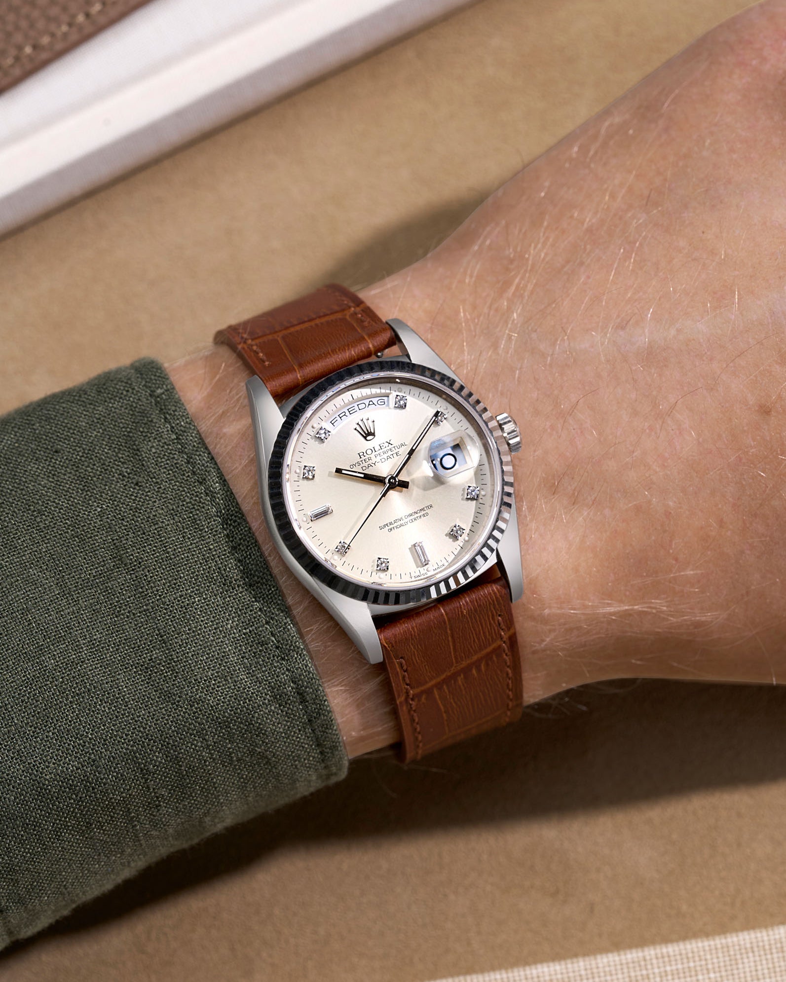 Rolex Daydate with diamond indexes watch with a brown alligator leather strap on a beige background