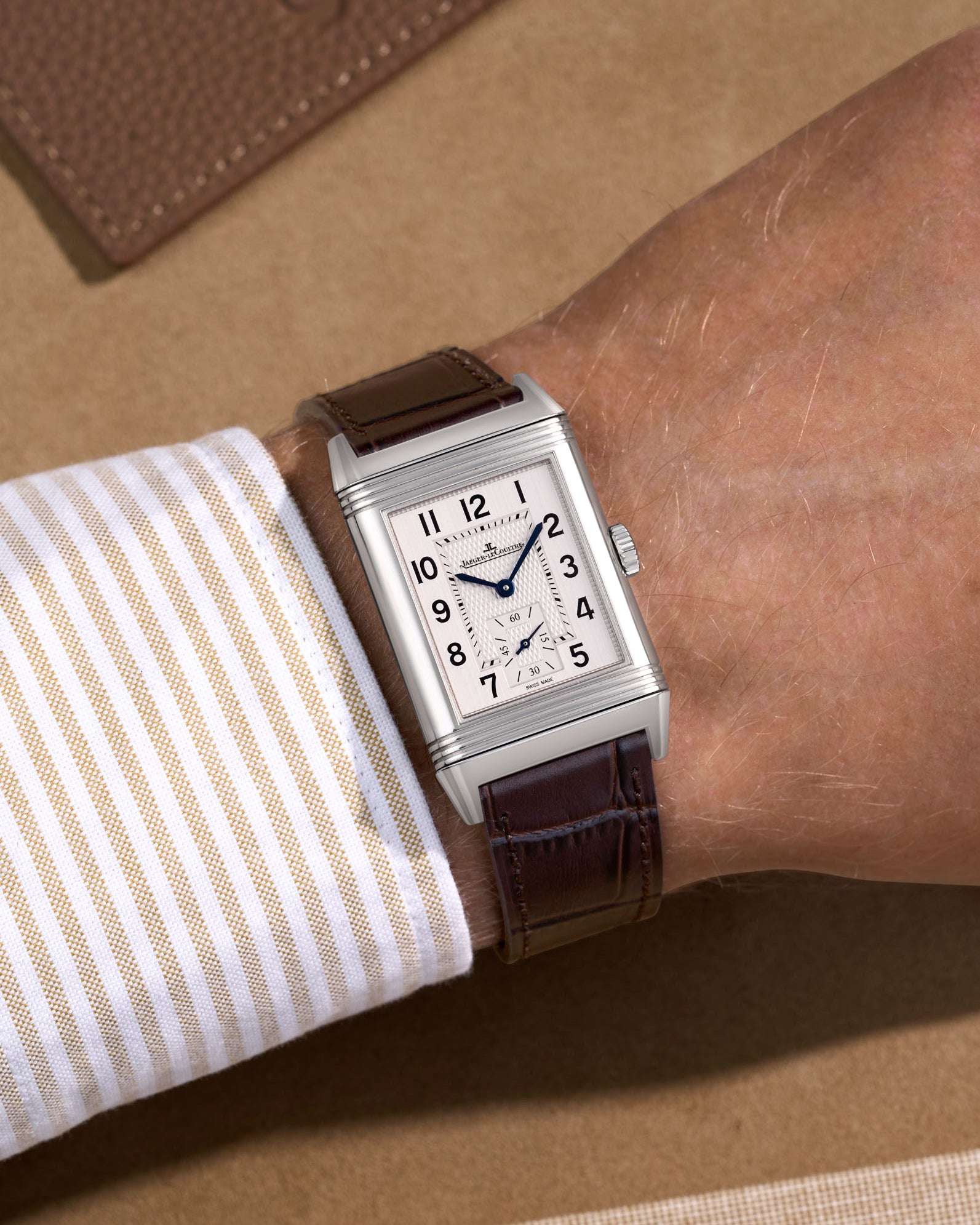 JLC Reverso watch with a dark brown alligator leather watch strap on a beige background