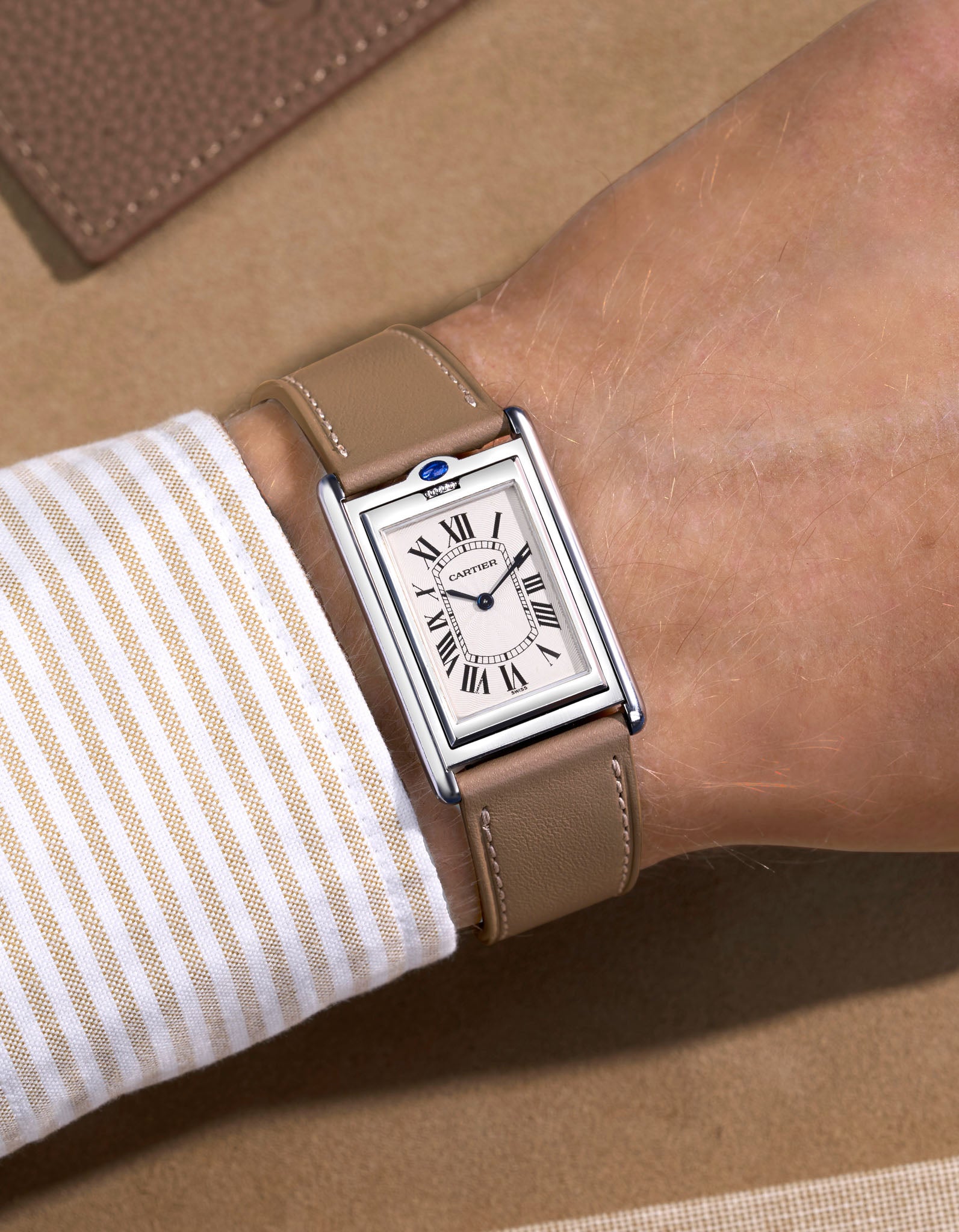 Cariter Basculante on a taupe cowhide leather watch strap on a wrist with a suede background
