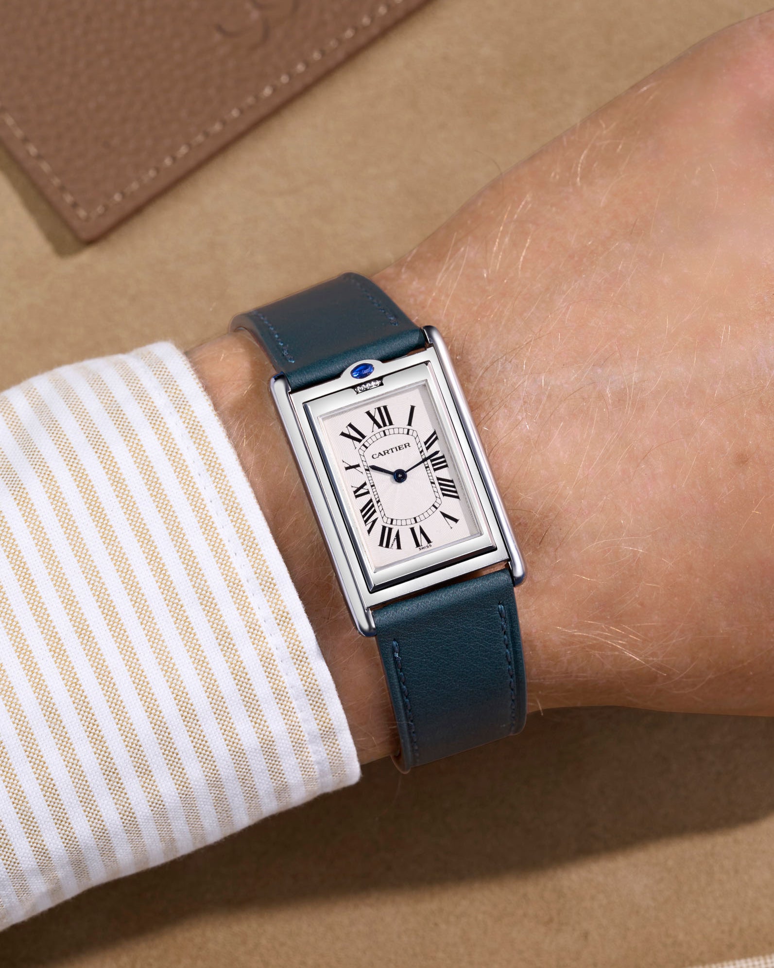 Cariter Basculante on a petroleum green cowhide leather watch strap on a wrist with a suede background